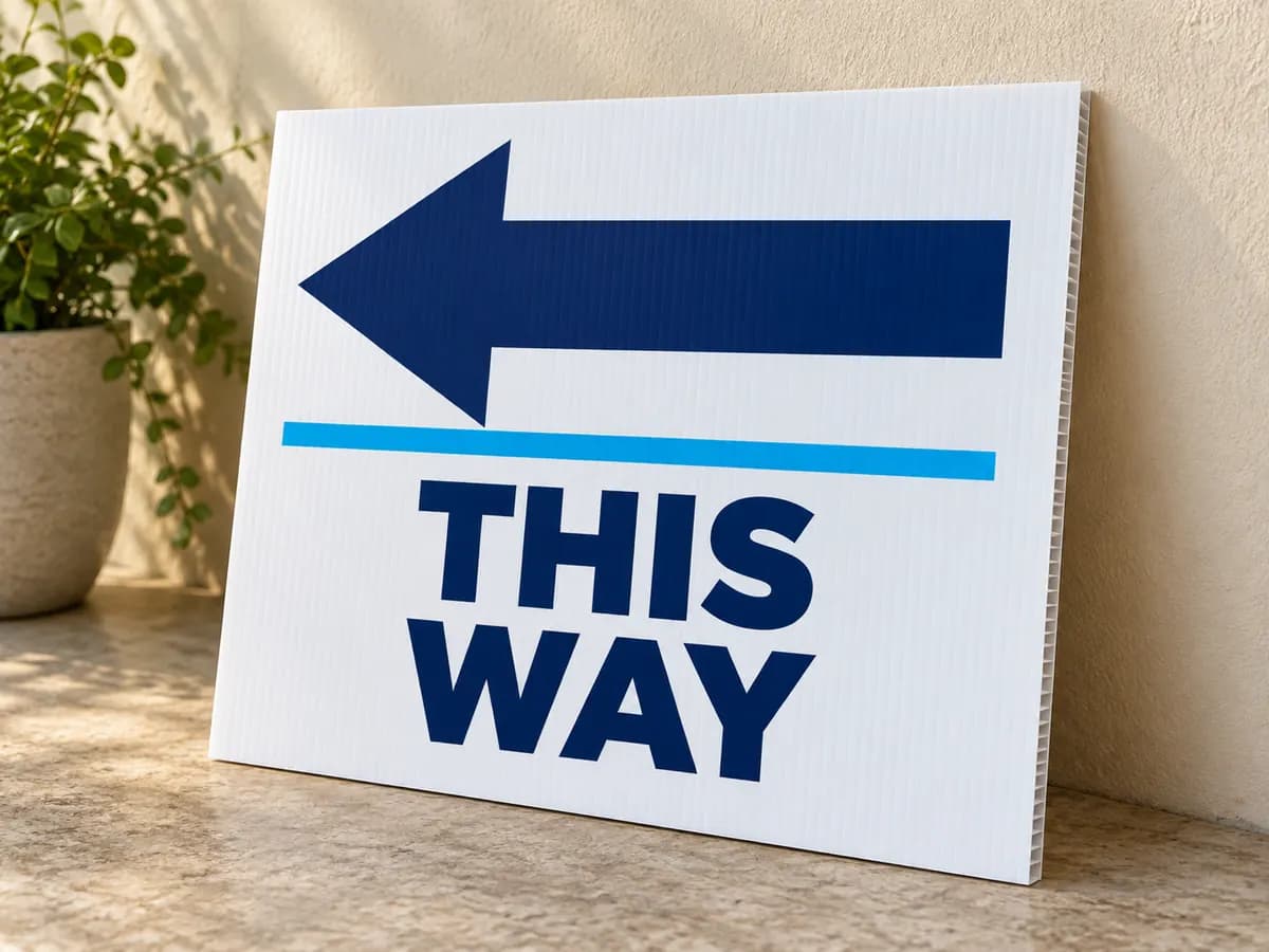 Illustrative white THIS WAY sign with a left arrow leaning against a wall